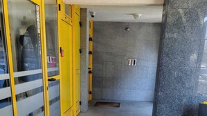 Un pasillo con un armario amarillo a la izquierda y una pared revestida de baldosas grises a la derecha.