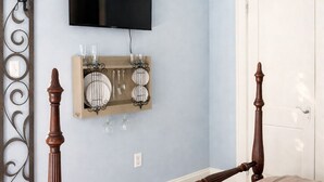Ein Schlafzimmer mit einem Bett, einem an der Wand befestigten Fernseher, einer Wanddekoration und einer Tür.
