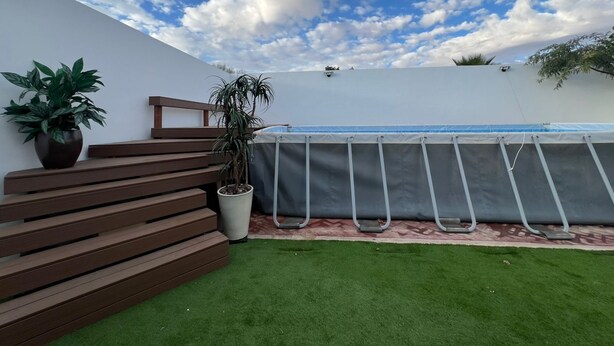 A pool area with a wooden deck, potted plants, and a clear blue sky. - Welcoming 3-bedroom house with AC and pool in Puerto Penasco (Puerto peñasco)