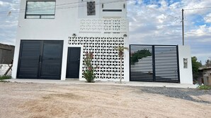 A modern two-story building with a white facade, featuring a large garage door, a decorative lattice wall, and a black gate. - Welcoming 3-bedroom house with AC and pool in Puerto Penasco (Puerto peñasco)