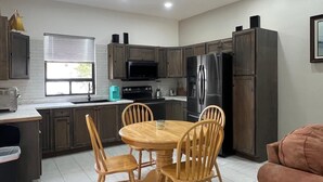 A modern kitchen with wooden cabinets, a stainless steel refrigerator, a microwave, and a dining table with chairs. - Welcoming 3-bedroom house with AC and pool in Puerto Penasco (Puerto peñasco)