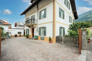 A multi-story building with a courtyard, a balcony, and a wooden fence. - Apartment in Salorno, courtyard and covered parking. (Salorno)