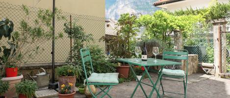 Un patio con una mesa y sillas, rodeado de plantas en macetas y vistas a la montaña.