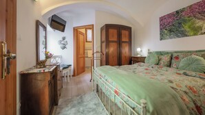 Ein Schlafzimmer mit Bett, Schreibtisch, Stuhl, Kleiderschrank und einem an der Wand befestigten Fernseher.