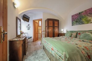 Une chambre à coucher comprenant un lit, un bureau, une chaise, une armoire et un téléviseur fixé au mur.