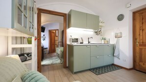 Eine gemütliche Küche mit einem grünen Schrank, einer Kaffeemaschine und einer Uhr an der Wand.