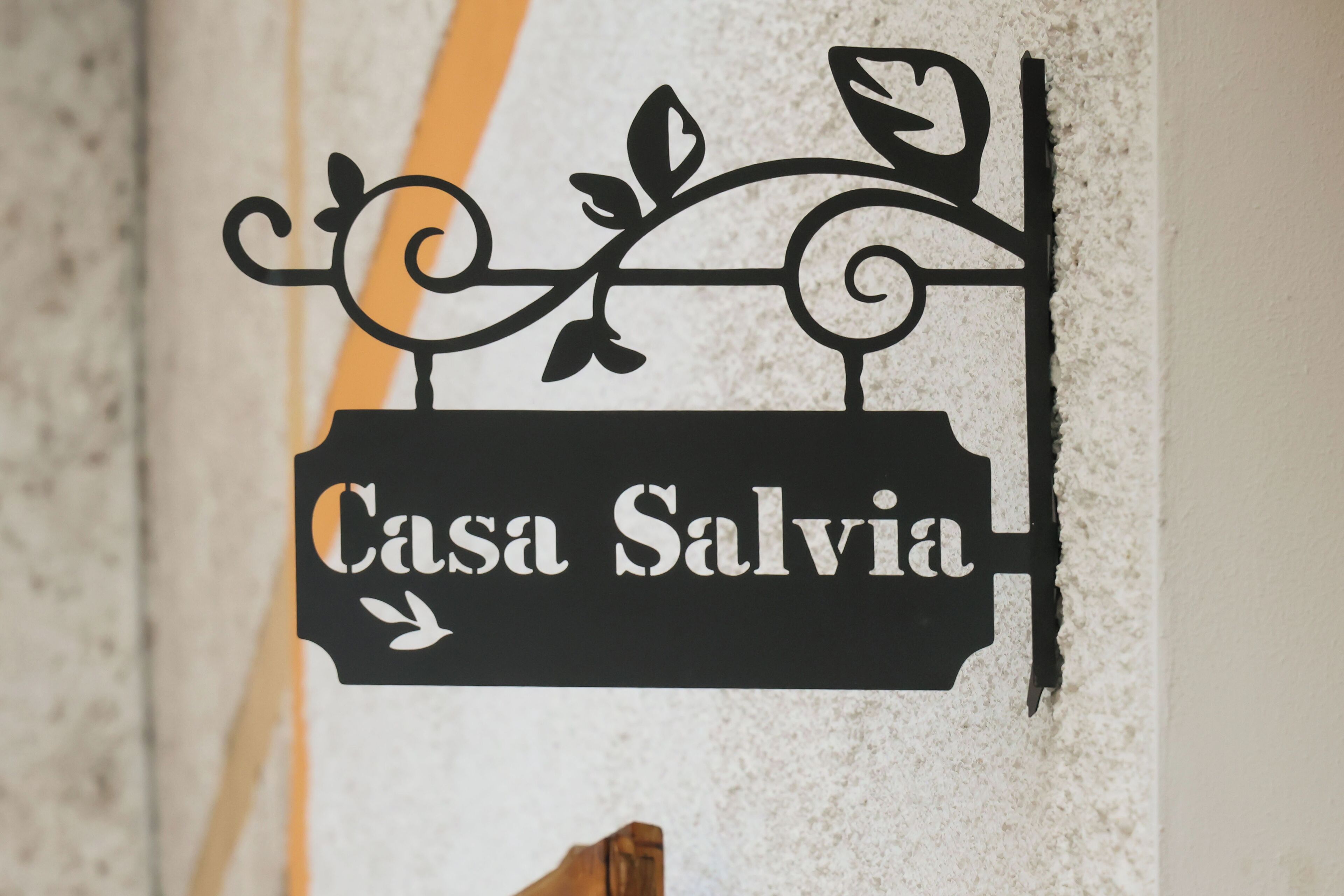 Un panneau noir avec l’inscription « Casa Salvia » et des éléments décoratifs.
