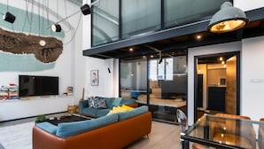 Una sala moderna con un sofá grande, una mesa de comedor de vidrio y un televisor.