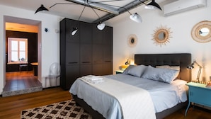 Un dormitorio con una cama grande, un armario, un escritorio y una silla. Hay dos lámparas de pared y una lámpara en el techo.