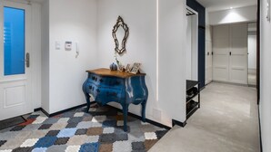 Un pasillo con un armario azul, un espejo decorativo y una alfombra estampada.