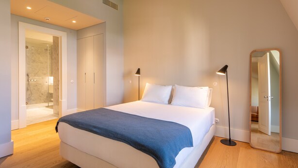 A modern bedroom with a large bed, bedside lamps, a mirror, and a walk-in closet. - FLH Heart of Rossio Apartment II (Lisboa ciudad)