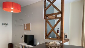 A modern living room with a dark wooden table, a red pendant light, a television, and a decorative basket. - FLH Bairro Alto Central Flat with Pateo (Lisboa ciudad)