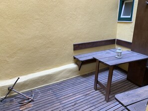 A wooden deck with a table and benches, a lantern, and a window with a green frame. - FLH Bairro Alto Central Flat with Pateo (Lisboa ciudad)