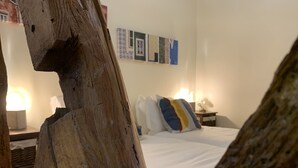 A bedroom with a wooden headboard, a bed with white bedding, and a nightstand with a lamp. - FLH Bairro Alto Central Flat with Pateo (Lisboa ciudad)