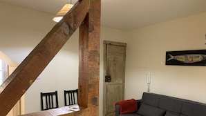 Un escalier en bois mène à un espace repas où se trouve un canapé gris et une œuvre d’art sur le thème des poissons est accrochée au mur.