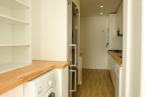 A narrow kitchen with a washing machine, a microwave, and a stove. - FLH Cascais Love apartment (Cascais)