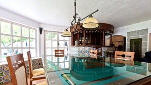A dining area with a glass-top table, chairs, and a bar area with a tiled backsplash. - FLH Yucca House Carcavelos Beach (Cascais)