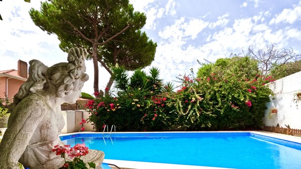 A stone statue of a woman holding a flower by a poolside. - FLH Yucca House Carcavelos Beach (Cascais)