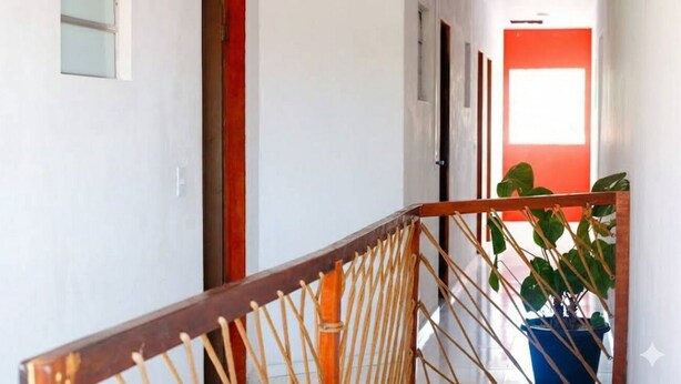 A staircase with a wooden handrail and a potted plant on the right. - Pousada Delta (São Luís)