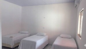 A room with three single beds, white walls, and a window on the right side. - Pousada Delta (São Luís)