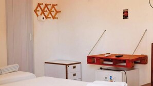 A hotel room with a bed, a small bedside table, a wooden shelf with a remote control, and a wall-mounted light fixture. - Pousada Delta (São Luís)