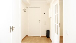 En hall med en vit dörr, en svart soptunna och en ljusströmbrytare på väggen.