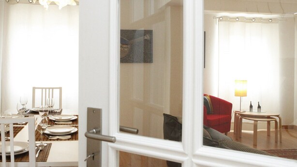 En matplats med ett bord dukat för fyra personer, en röd soffa och en lampa.