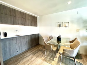 Une cuisine moderne avec une table et des chaises en verre, des armoires en bois et un évier encastré.