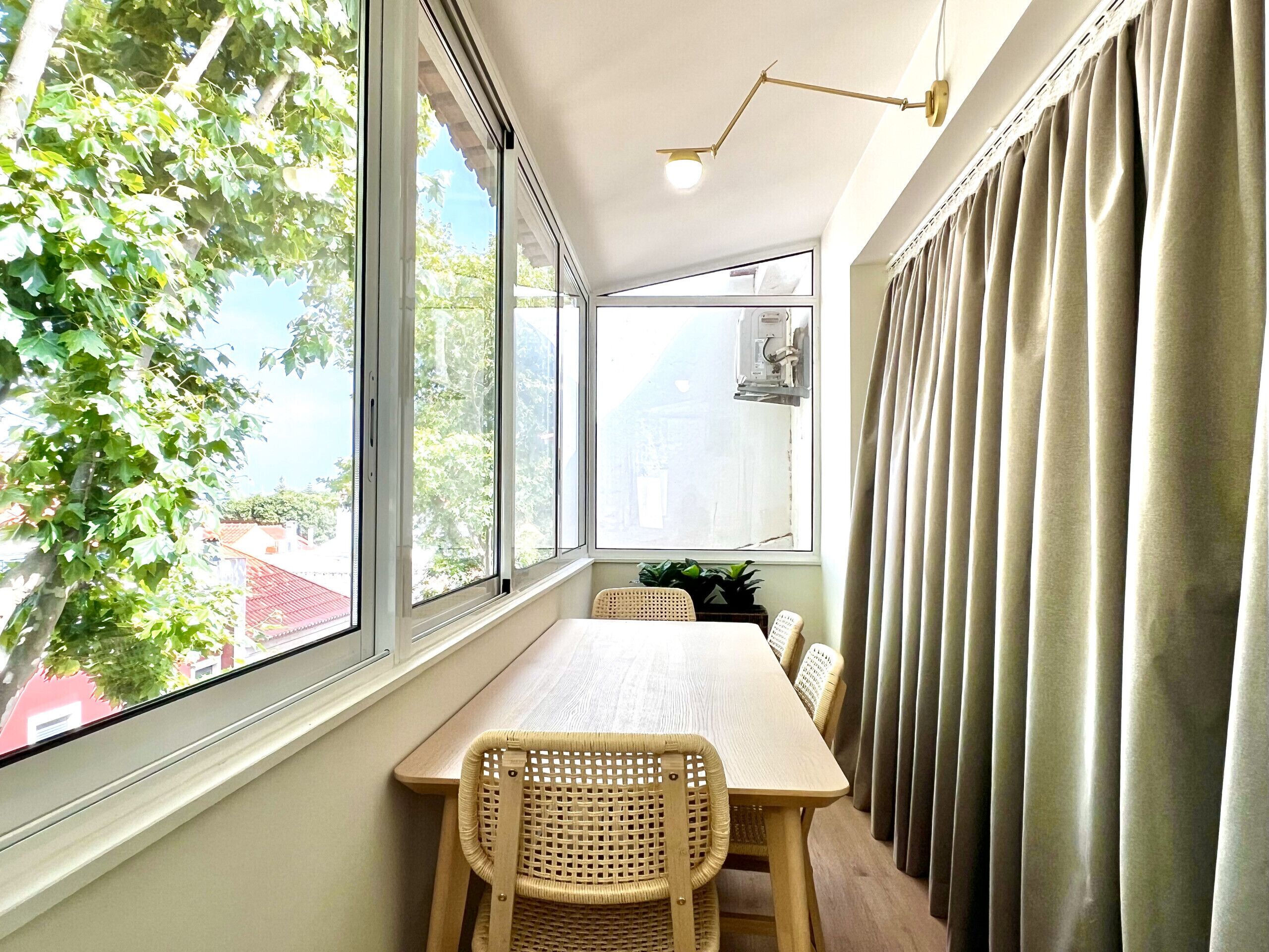 A room with a large window, a table, chairs, and a lamp.