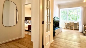 Una sala de estar moderna con piso de madera, un comedor con mesa y sillas, y un ventanal con vista a la vegetación.