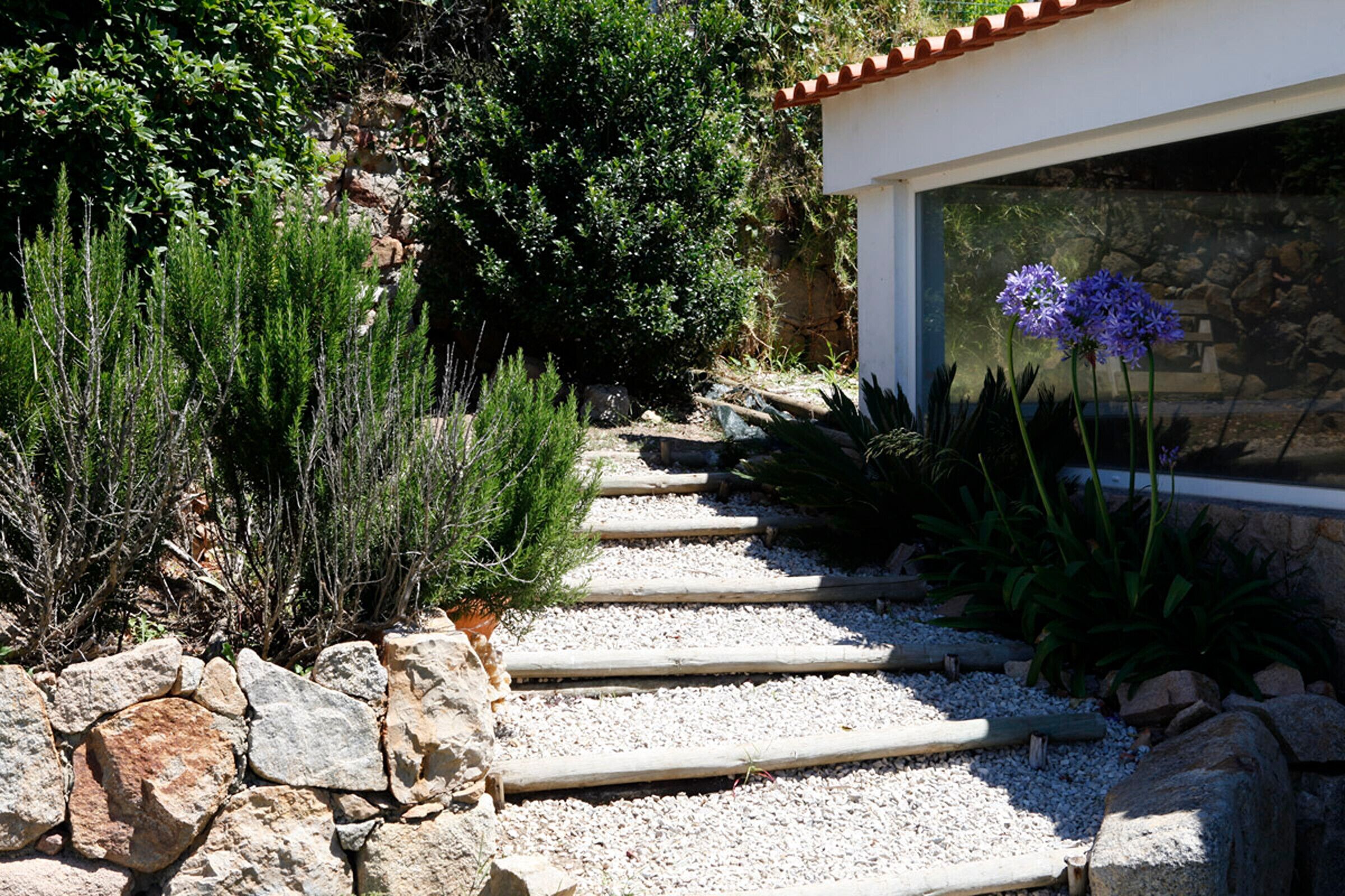 A stone pathway leading to a building with a white exterior and red roof tiles.