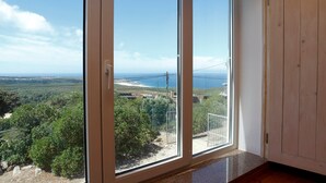 Una habitación con un amplio ventanal corredera que da a un balcón con vistas panorámicas de la costa y la vegetación.