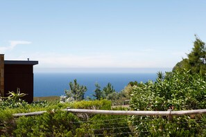 Une vue sur la côte, avec une clôture en bois, de la végétation et un bâtiment au premier plan.