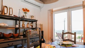 Un comedor con una mesa dispuesta para dos personas, que incluye una botella de vino, copas y platos.