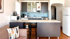 Eine moderne Küche mit einer zentralen Kochinsel, Barhocker, einer Mikrowelle, einer Kaffeemaschine und einem Kühlschrank.