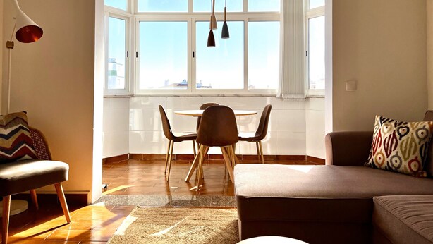 Ein modernes Wohnzimmer mit Essbereich, großen Fenstern und Blick auf die Stadt.