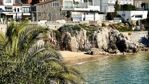 Un edificio frente al mar con fachada de piedra, un balcón y vistas a la playa y al océano.
