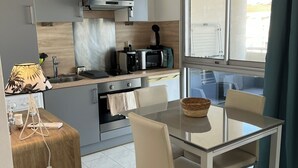 Una cocina moderna con comedor, que incluye una mesa de vidrio, sillas y vistas a través de una ventana.