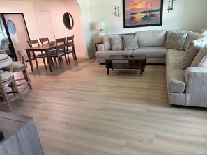 A living room with a sofa, a coffee table, and a dining area with chairs and a table.