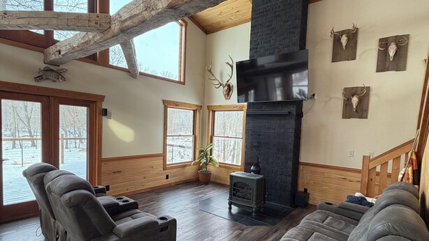 Amplia sala de estar con pisos de madera, ventanas grandes, una chimenea y dos sillones reclinables.