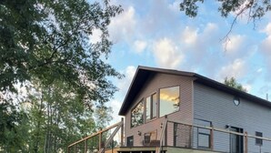Una casa de dos pisos con una escalera de madera que conduce a una terraza.
