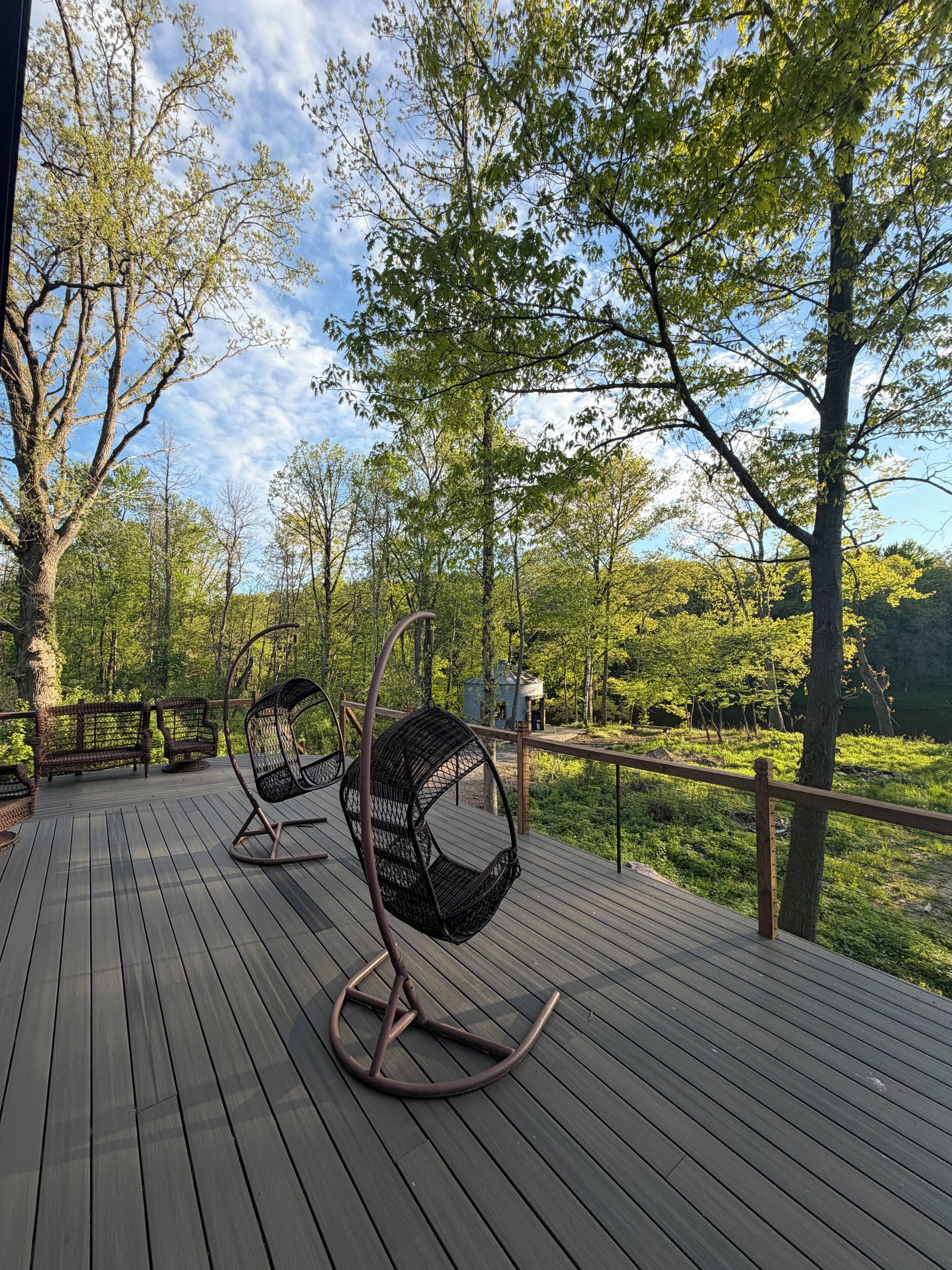 Eine Holzterrasse mit Korbstühlen und Blick auf einen Wald.