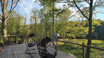 Eine Holzterrasse mit Korbstühlen und Blick auf einen Wald.