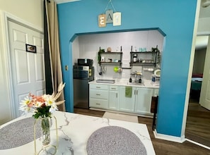 Cucina con mobili bianchi, un forno a microonde e un lavello. Sul tavolo, un vaso con fiori.