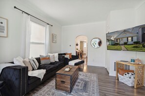 Ein modernes Wohnzimmer mit einem schwarzen Sofa, einem Holztisch und einem an der Wand befestigten Fernseher.