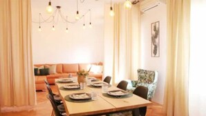 A dining area with a wooden table set for four, surrounded by chairs. There is a sofa in the background and a patterned armchair to the side. - Dare Apartment with private pool and garden (Kaštel Sućurac)