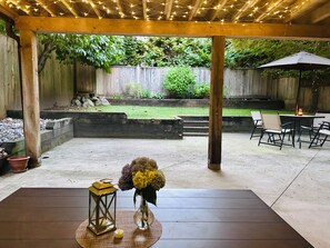 Un patio exterior con una mesa, sillas, un farol y un jarrón con flores.