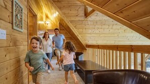 A wooden interior with a staircase, a brown leather couch, and a table. - Amazing Grace - Charming Cabin (Sevierville)