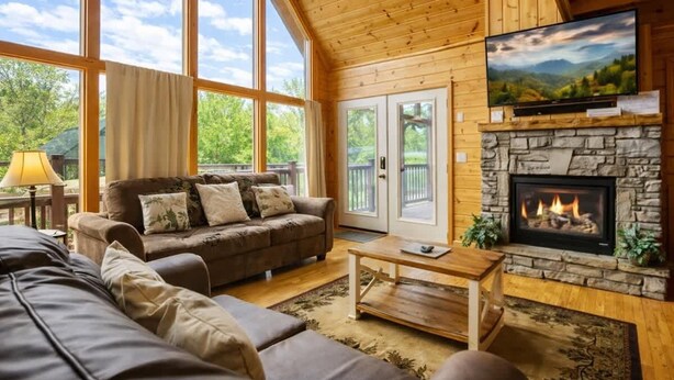 A cozy living room with a stone fireplace, a large TV, and a comfortable sofa. - Amazing Grace - Charming Cabin (Sevierville)