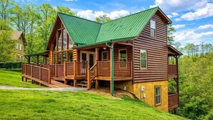 A two-story log cabin with a green roof, a deck, and a porch. - Amazing Grace - Charming Cabin (Sevierville)